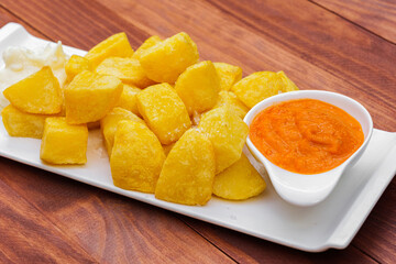 Fast food french fried potato with sauce on white plate and wooden background.