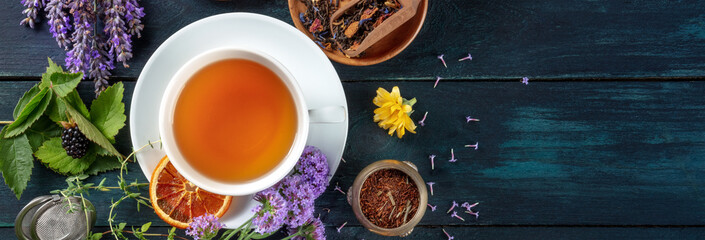 Tea panorama with a place for text. Herbs, flowers and fruit around a cup of tea, an overhead flat...