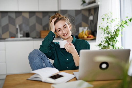 Young woman student with laptop drinking coffee, home office and learning.