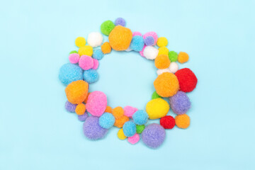 Circle of colorfull fluffy balls on blue background. Pile of colorfull fluffy balls. Fluffy textile balls circle frame on blue background.