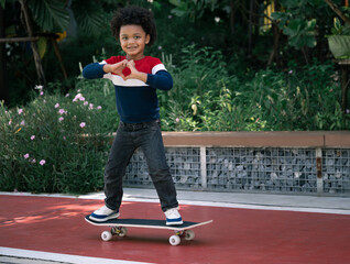 Happy kid boy with afro hair and skateboard in the park


