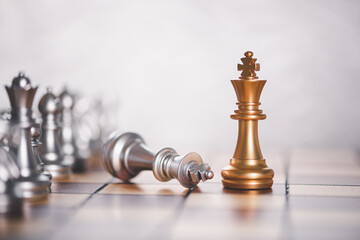 a gold chess surrounded by a number of silver chess pieces , business strategy concept