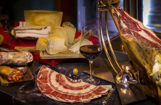 Bodeg&oacute;n de quesos, jam&oacute;n y embutidos. Copa de vino tinto con embutidos.