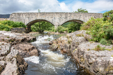 Fototapeta na wymiar River flowing under a double arched bridge in the Highlands of Scotland