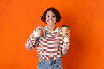Young brunette woman showing thumb up while drinking coffee