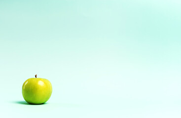 Green apple on a blue background. Copy space. 