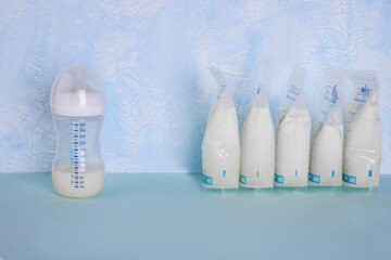 Bags with breast milk on blue background. Befrosting milk. Milk bottle. Working mom. Milk bank. Expressing breast milk. Breast-feeding. Freezing and storing milk. Donated milk.Copyspace - obrazy, fototapety, plakaty
