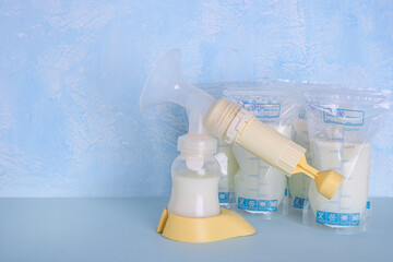 Bags with breast milk. Breast pump on blue background. Milk bank. Expressing breast milk....