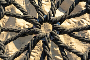 cuerdas negras formando un patrón con fondo de arena