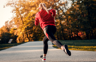 Rear view of young woman running in park.