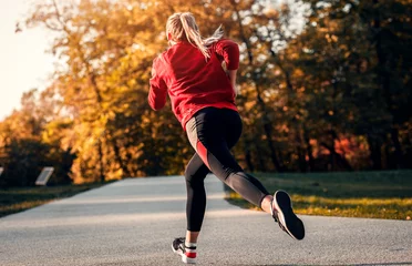 Tuinposter Rear view of young woman running in park. © Zoran Zeremski