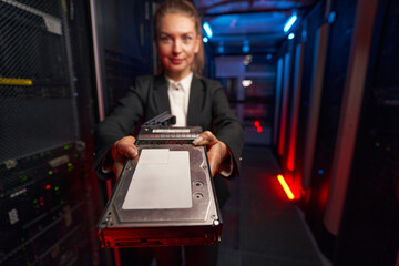 Female technician holding hard drive disk in data center
