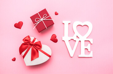 Valentine's Day. Gifts in the form of hearts on a pink background with the inscription love. Copy space for text. The concept of romance and love.