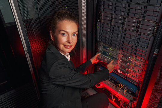 Computer technician working with backup server in racks - Powered by Adobe