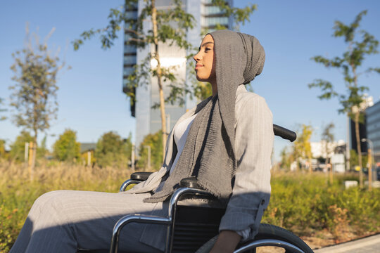 Young disabled woman looking away while sitting on wheelchair during sunny day