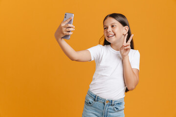 White brunette girl gesturing while taking selfie on mobile phone