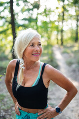 Fototapeta premium Portrait of active senior woman runner standing outdoors in forest.