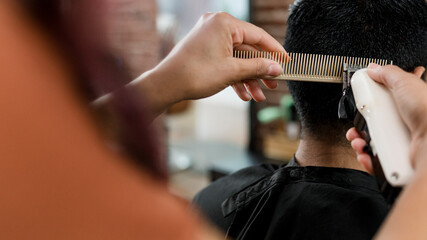 Hairdresser trimming hair of the customer at a barbershop