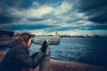 Obraz premium Girl looks in binoscope on city. St. Petersburg