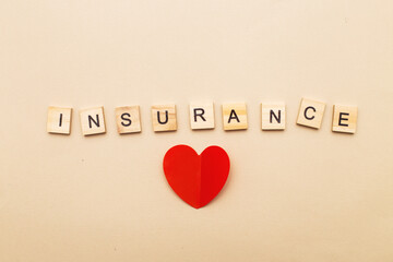 inscription insurance on a beige background made by wooden blocks with red heart