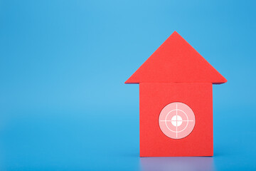 Obraz na płótnie Canvas Red toy house with target in the middle against blue background with copy space. Concept of real estate, loan or mortgage