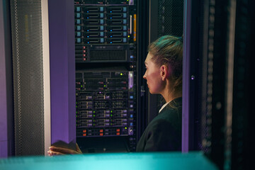 Professional young woman working in server room