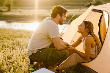 White couple smiling and hugging during camping on summer day