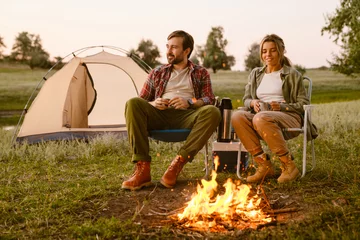 Cercles muraux Camping White couple smiling and drinking tea during camping together