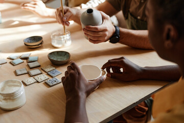 Diverse group of people enjoying pottery class in cozy studio, close up, copy space