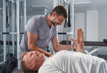 Physiotherapist doing healing treatment of man hand on massage table