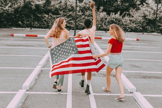 Women celebrating Independence Day, holding American flag rear view