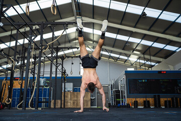 Young male athlete doing handstand in gym