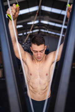 Shirtless male athlete standing by exercise machine in gym