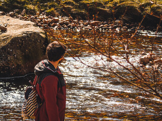 A man from behind looking a river on a hike
