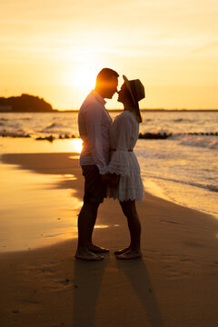 Boyfriend rubbing nose with girlfriend at beach on sunset