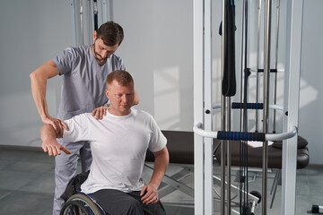 Manual therapist treats man with disability shoulder joint flexibility