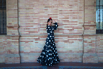 Spanish, beautiful, brunette flamenco dancer in a typical flamenco dress with white polka dots. She...