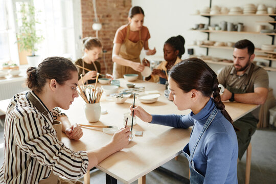 High angle shot of diverse group of people decorating ceramics in pottery workshop, copy space