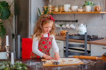 little girl making cookies for christmas in the kitchen