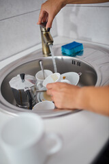 Unrecognizable woman housewife washing dishes in the kitchen at home over sink, lifestyle, House equipment.