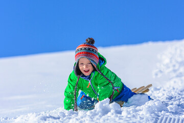 kleiner Junge beim Schlittenfahren im Winter