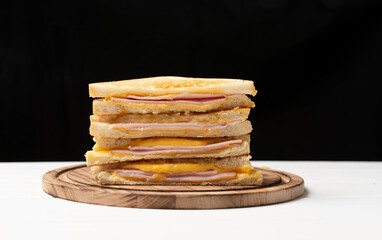 Toast with ham and cheese on a wooden board.