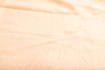 Fragment of smooth orange linen tissue. Side view, natural textile background.