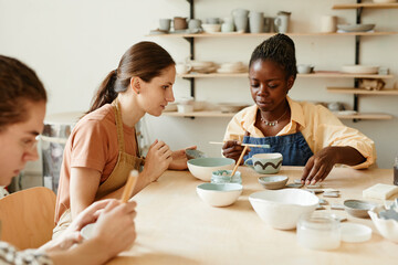 Side view portrait of young woman enjoying pottery workshop in cozy studio, copy space