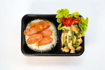 Chinese food lunch box in plastic packages, Rice with Chinese Chicken in Brown Sauce and Chinese Sausage.