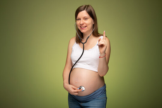 Pregnant woman with stethoscope trying to hear her baby heartbeat by herself. Worrying in pregnancy. Woman with tammy preparing for the birth of the baby.
