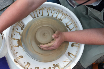 Fototapeta premium Close up hands working on pottery wheel and making a clay pot, selective focus