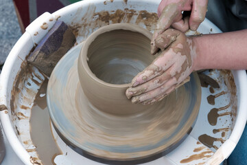 Close up hands working on pottery wheel and making a clay pot, selective focus