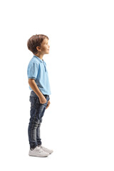 Full length profile shot of a boy in a blue t-shirt standing and watching something