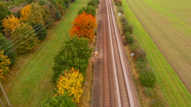 Flying over railway track beside a autumn forest in Thetford, England - aerial drone backward shot